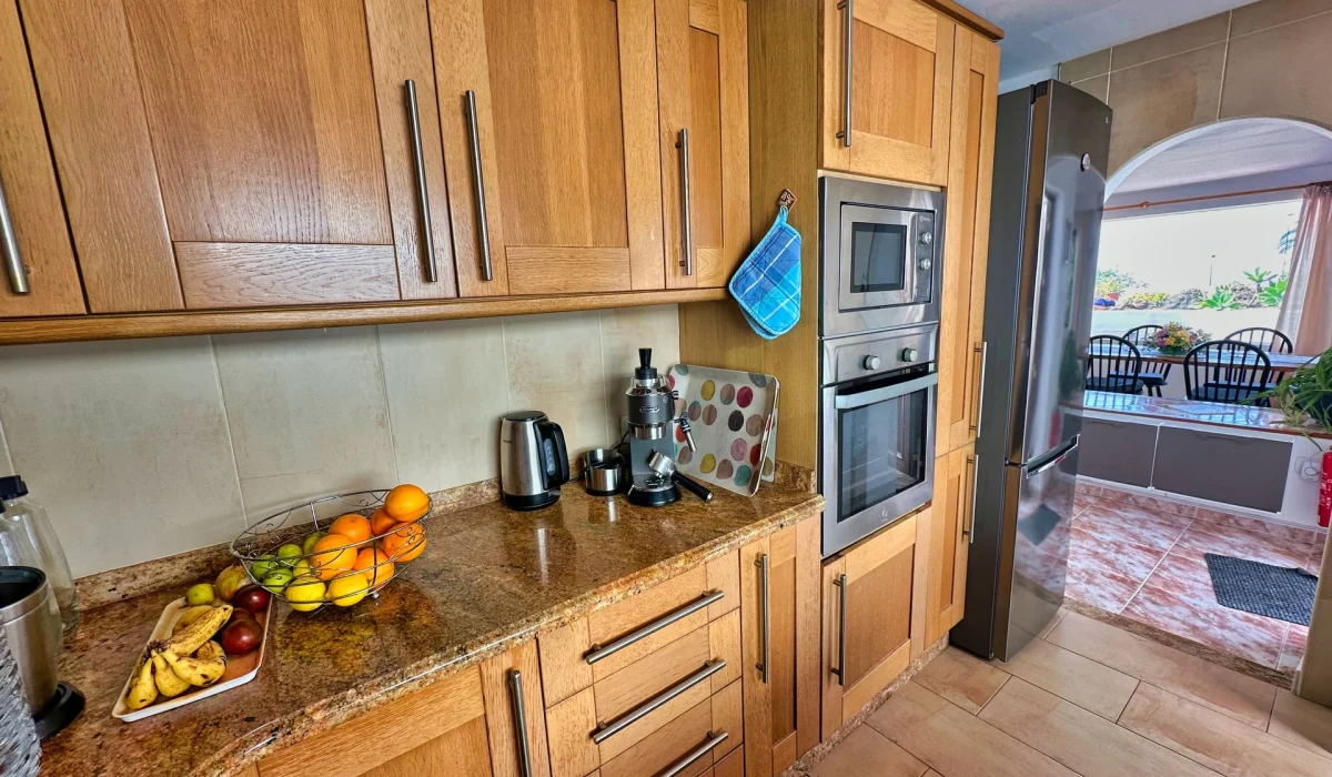 Kitchen with oven, microwave and fridge, opening to the dining area