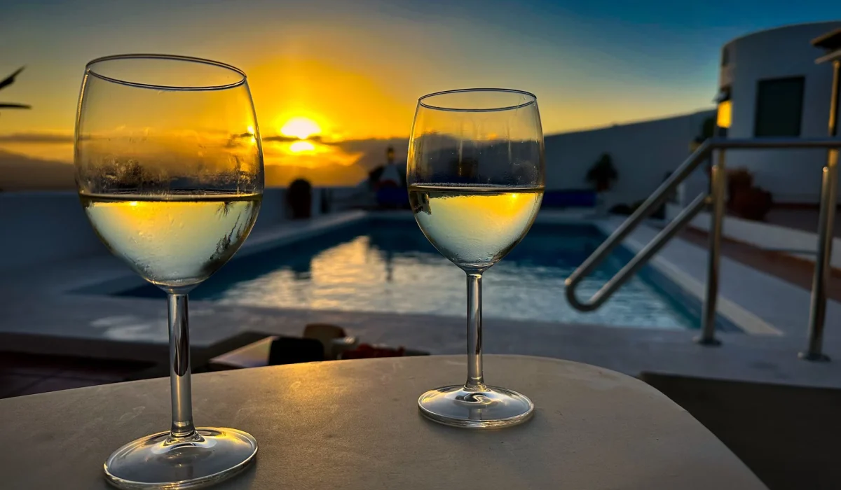 Two glasses of white wine by the pool at sunset